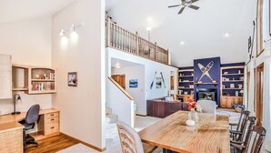 A spacious living area with a wooden dining table, a sofa, and a bookshelf. - Spacious Pet-Friendly Lake Home with 2 Kitchens – Perfect for Family Gatherings (Lac du Flambeau)