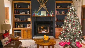 A cozy living room with a fireplace, a Christmas tree, and a fireplace mantel with decorations. - Spacious Pet-Friendly Lake Home with 2 Kitchens – Perfect for Family Gatherings (Lac du Flambeau)
