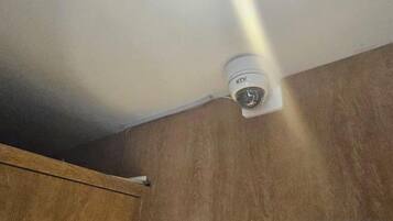 A ceiling-mounted security camera in a room with wooden walls.