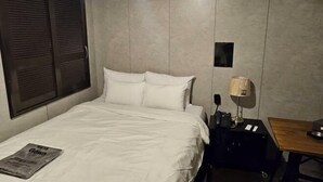 Ein Hotelzimmer mit einem Bett, einem Nachttisch, einer Lampe und einem kleinen Tisch.