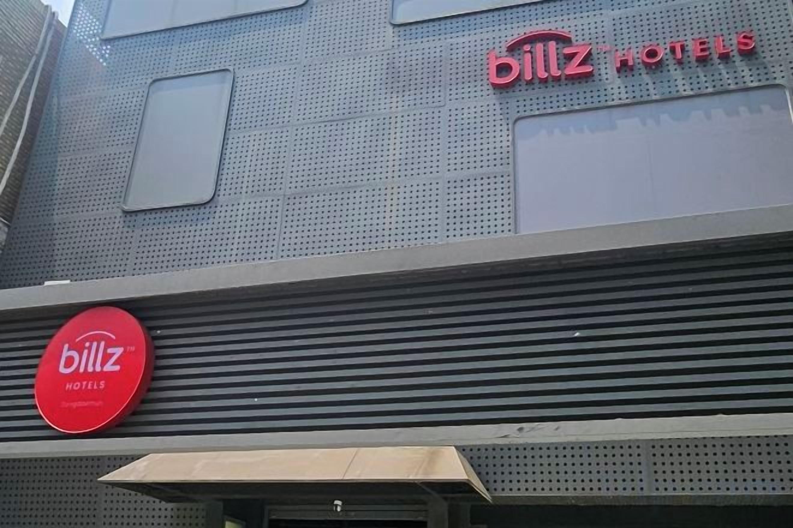 A hotel exterior with a prominent 'billz hotels' sign and a large circular logo.