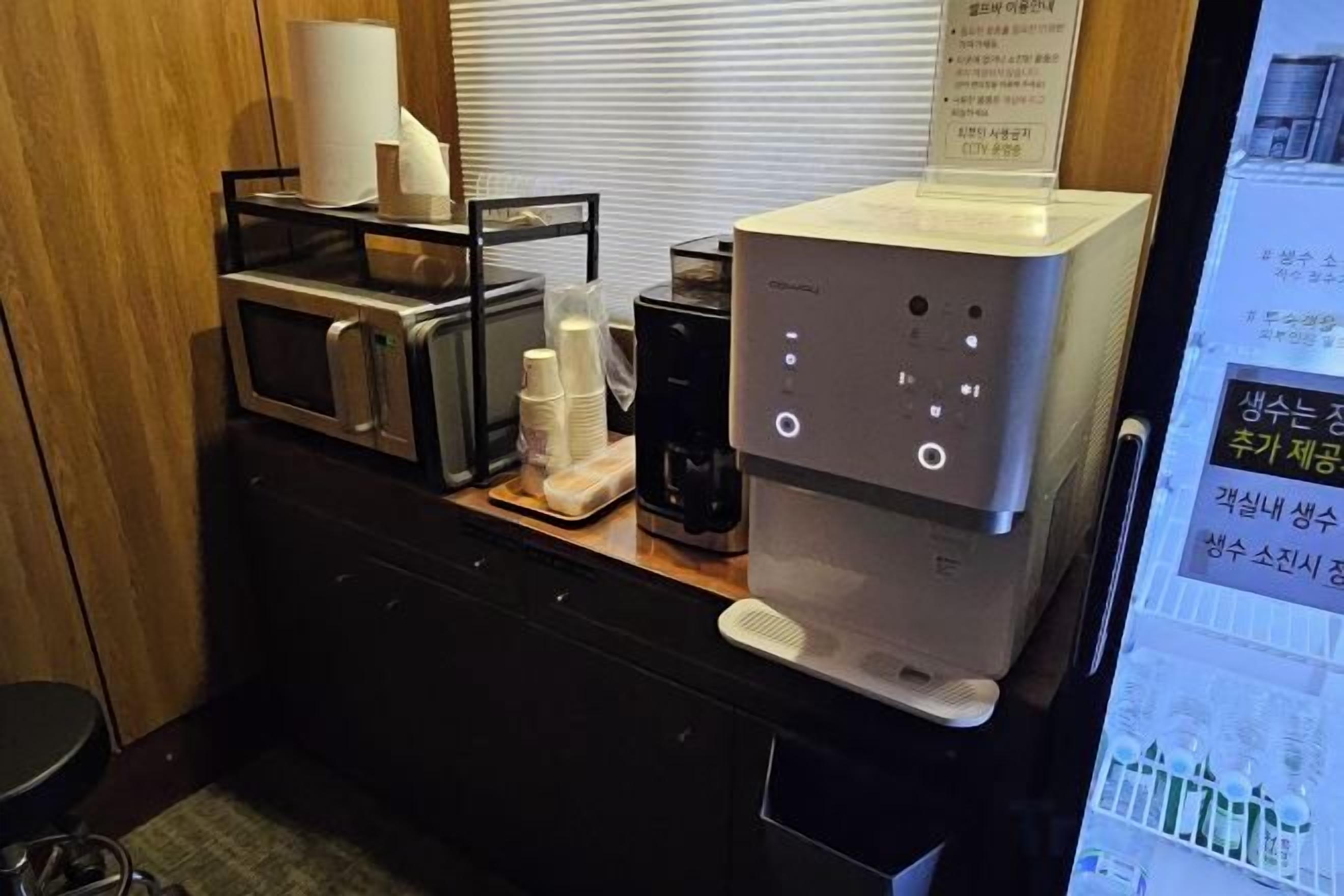 A kitchenette with a microwave, coffee maker, and a digital coffee machine.