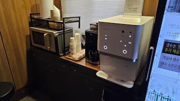 A kitchenette with a microwave, coffee maker, and a digital coffee machine.