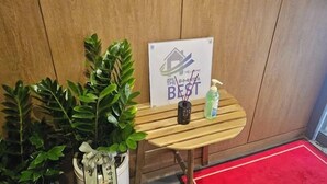 Ein Holztisch mit einem Schild, das eine 'Best'-Auszeichnung zeigt, einer Zimmerpflanze und einer Flasche Handdesinfektionsmittel.