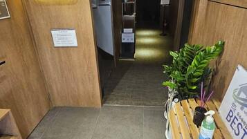 A hotel reception area with a wooden reception desk, a plant, and a sign indicating the hotel name.