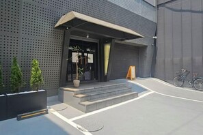 A modern building with a dark facade, a covered entrance, steps leading to the door, and a bicycle parked outside. - Billz Hotel Dongdaemun (Seoul)