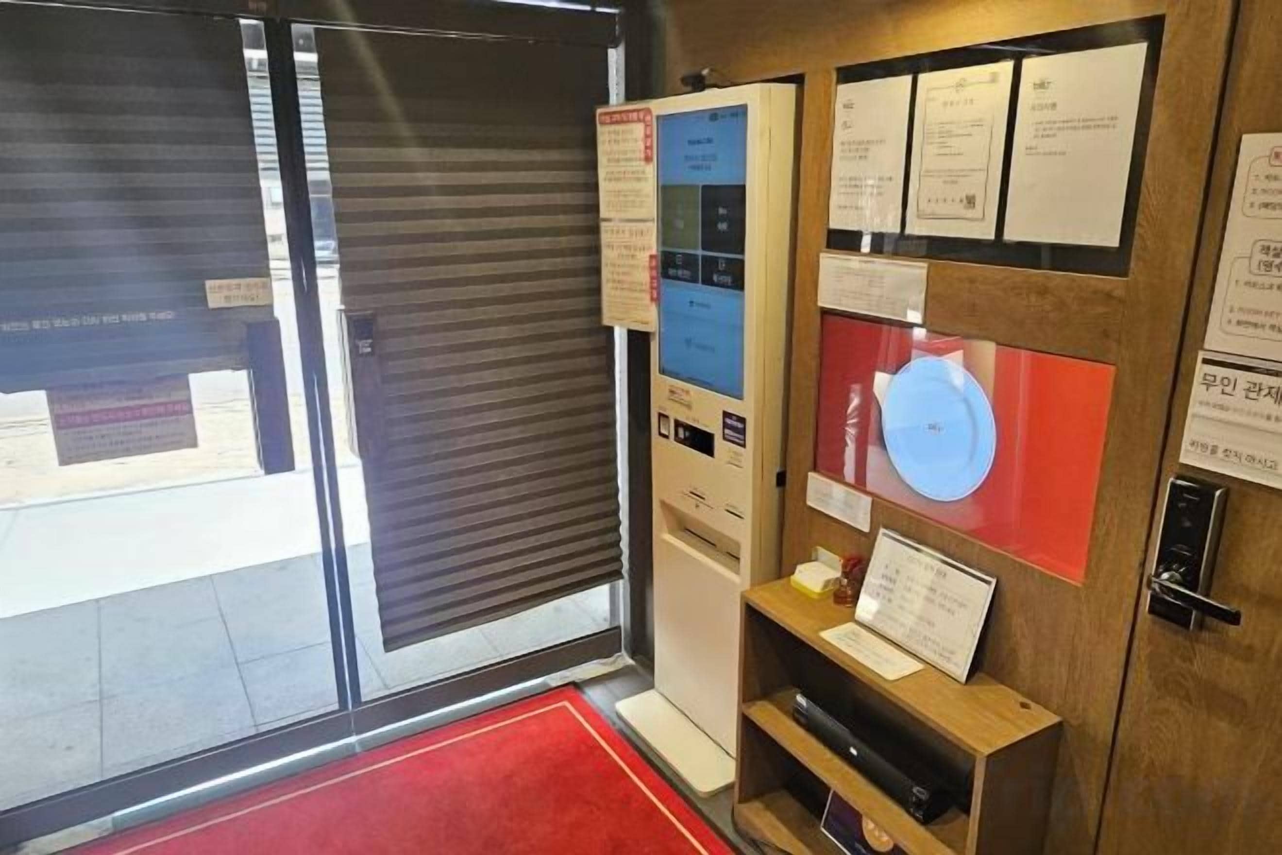 A room with a closed sliding door, a red carpet, and informational posters on the wall.
