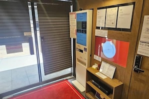 Een kamer met een gesloten schuifdeur, een rood tapijt en informatieposters aan de muur.