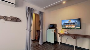 A modern hotel room with a wooden floor, a flat-screen TV mounted on the wall, a small refrigerator, and a desk with a lamp. - belivin'98 Sense of Pier Sathorn (Bangkok)
