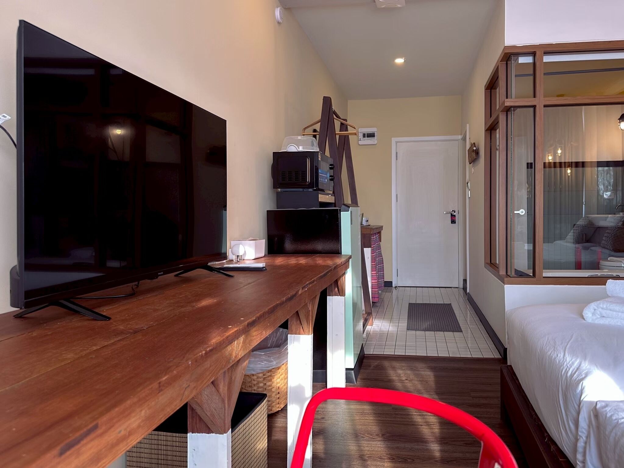 A hotel room with a wooden desk, a television, a bed, and a window with curtains.