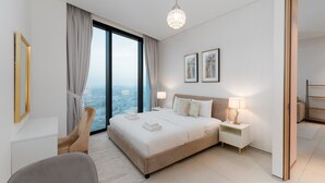 A modern hotel room with a large bed, bedside tables, a chair, and a view of the city. - Modern 1BR w/ Marina View Balcony at Address JBR (Dubai)