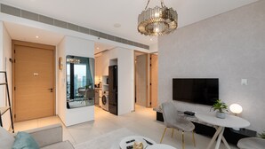 A modern living room with a sofa, a dining table, a TV, and a kitchen in the background. - Modern 1BR w/ Marina View Balcony at Address JBR (Dubai)