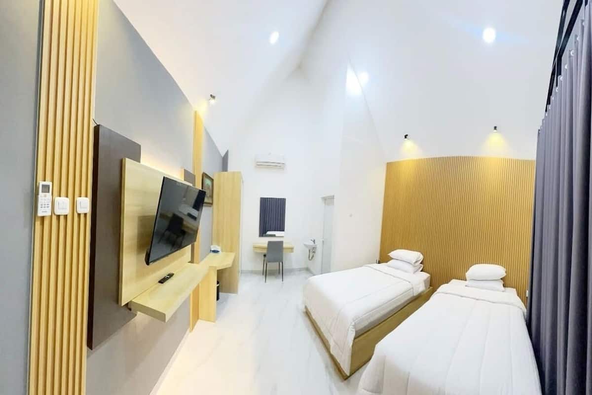 Une chambre d’hôtel moderne équipée d’une télévision, de deux lits, d’un bureau et d’un espace douche.