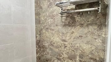 Een badkamer met een marmeren wand, toilet en handdoekhouder.
