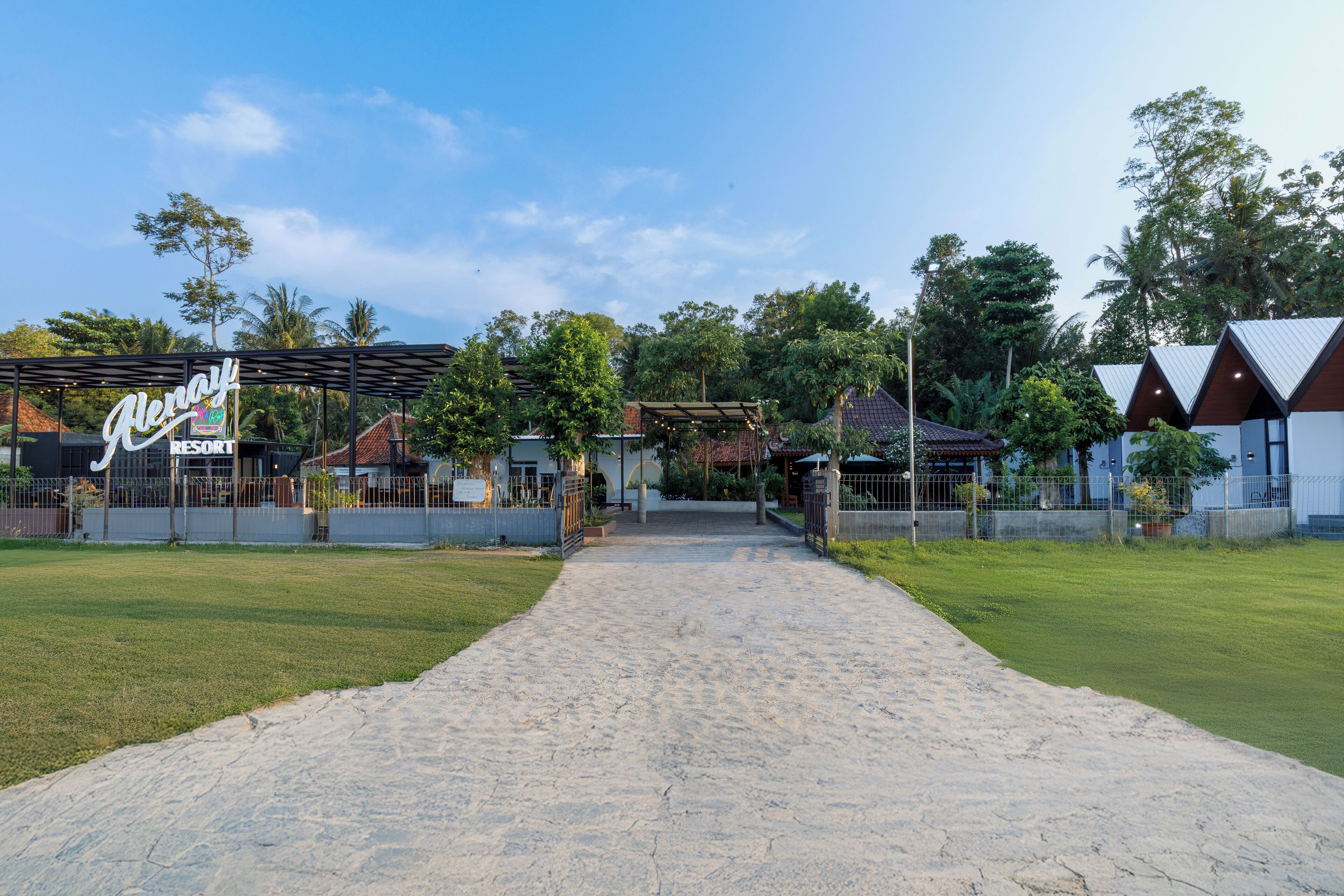 A pathway leading to a resort with a sign reading "Alemay Resort".