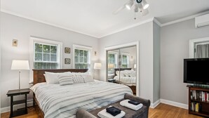 A bedroom with a large bed, bedside tables, a TV, and a bookshelf. - 6 bedrooms! Hot tub/firepit/deck/Pet friendly close to beach! (Kennebunk)