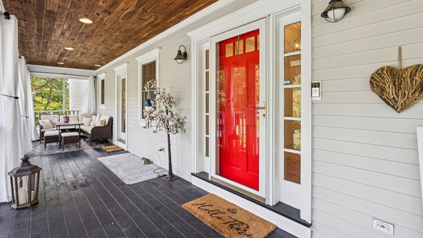 A covered porch with a wooden ceiling, white siding, a red door, and a bench area with cushions. - 6 bedrooms! Hot tub/firepit/deck/Pet friendly close to beach! (Kennebunk)
