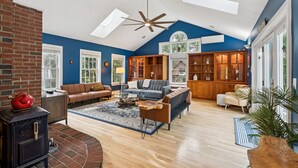 A spacious living room with a high ceiling, a fireplace, a large sofa set, and built-in wooden shelving. - 6 bedrooms! Hot tub/firepit/deck/Pet friendly close to beach! (Kennebunk)