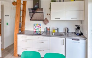 A compact kitchen with white cabinets, a stainless steel sink, and a compact refrigerator.