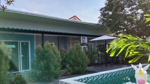 A modern building with a pool, surrounded by greenery and outdoor furniture. - Bunk Ubon Hostel (Ubon Ratchathani)
