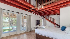 Un dormitorio con cama de madera, una escalera y vistas a una piscina.