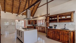 Una cocina amplia con una isla grande, armarios de madera y techo de paja.