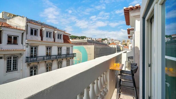 Ein Balkon mit Blick auf Gebäude und einen klaren Himmel.