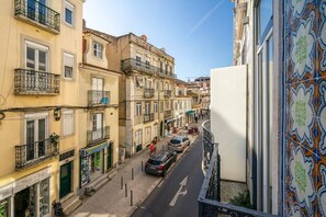 A narrow street with buildings on either side, featuring balconies and storefronts. - Alcântara Smart Studio | AC | Lx Factory (Lisboa)
