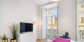 Ein modernes Wohnzimmer mit Flachbildfernseher, Lampe und Blick auf die Stadt durch große Fenster.
