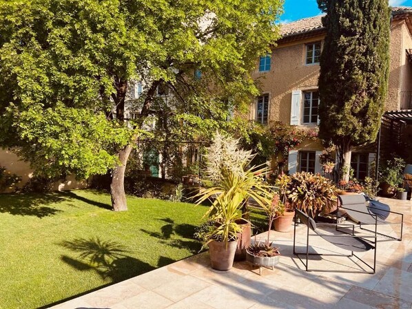 A courtyard with a lawn, potted plants, and outdoor seating. - Maison Jacotte (Orange)
