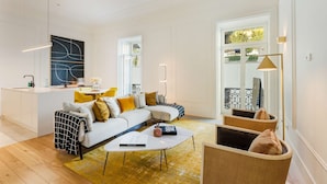 A modern living room with a sofa, coffee table, and wicker chairs. - Liberdade Deluxe Apartment | AC | S-Pool | Parking (Lisboa)