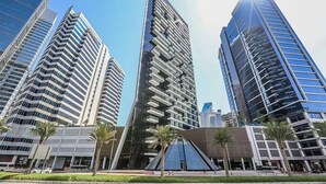A modern urban area with high-rise buildings, palm trees, and a clear sky. - Marquise Square Towers - Business Bay (Dubai)
