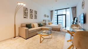 A modern living room with a sectional sofa, a glass coffee table, and a floor lamp. - Marquise Square Towers - Business Bay (Dubai)