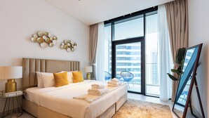 A modern hotel room with a large bed, a view of the city, and a balcony with a chair. - Marquise Square Towers - Business Bay (Dubai)