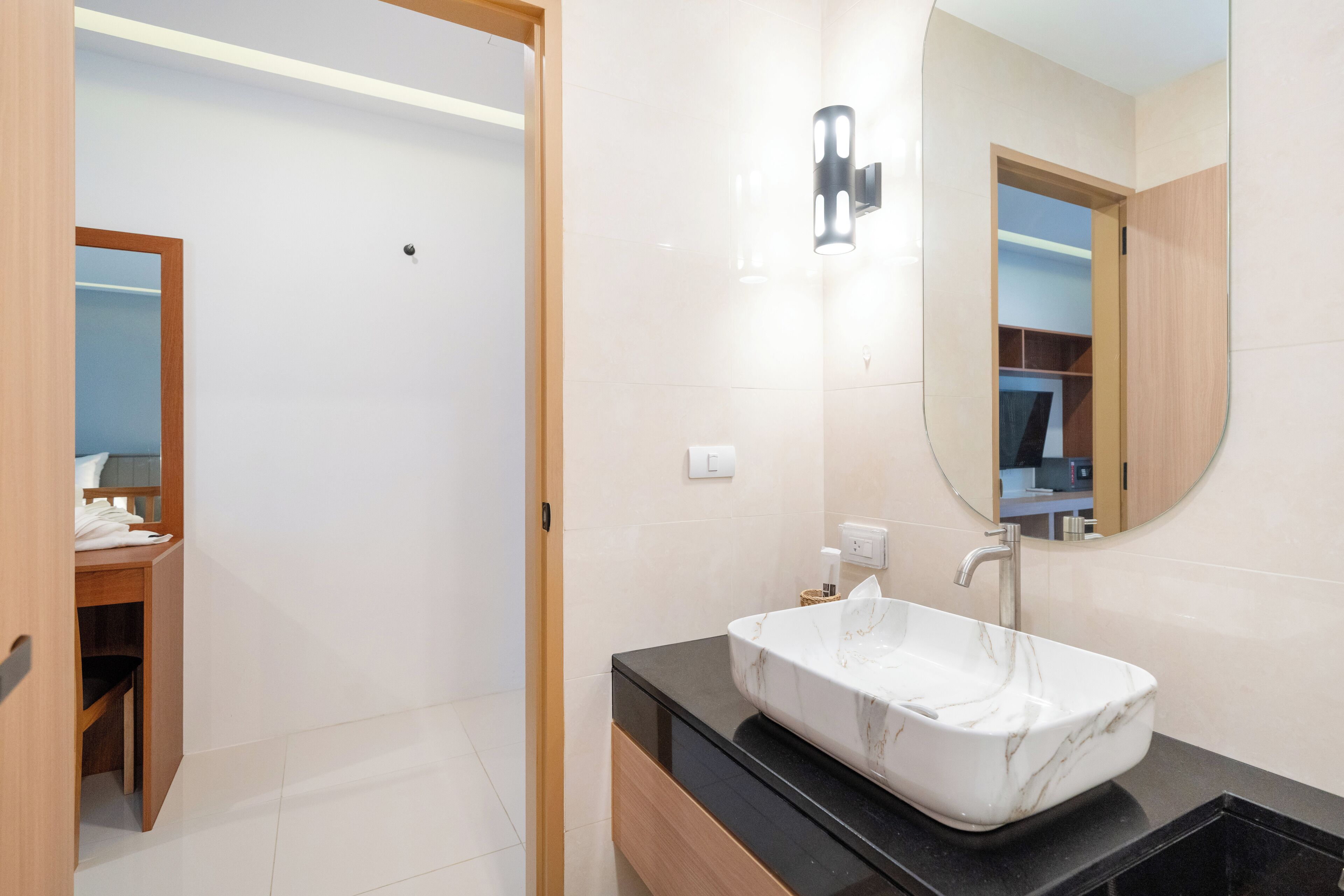 A modern bathroom with a marble sink, wooden vanity, and a large mirror.