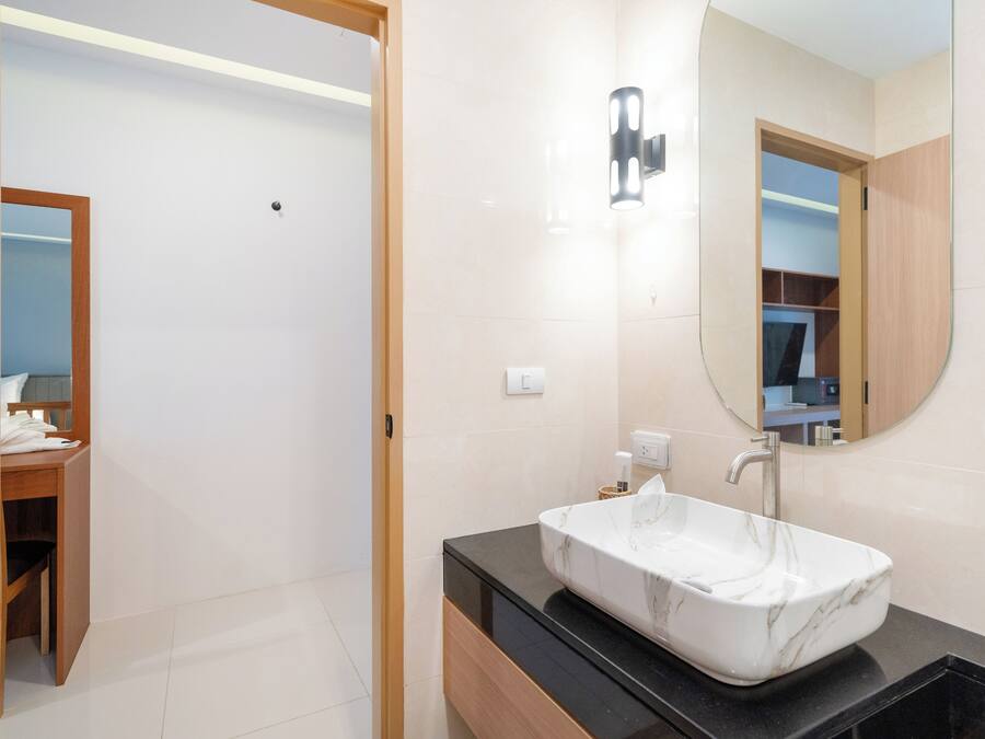 A modern bathroom with a marble sink, wooden vanity, and a large mirror.