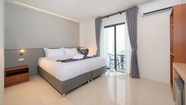 Una camera d'hotel moderna con un letto grande, un comodino, un armadietto in legno e vista all'esterno.