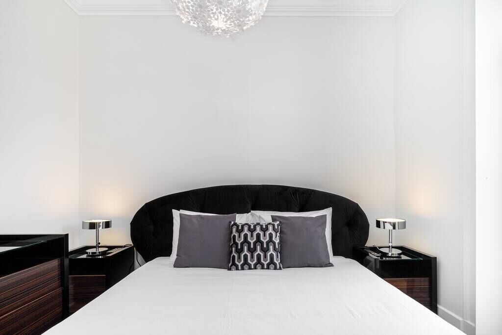 Una habitación de hotel moderna con una cama grande, dos mesitas de noche y un candelabro.