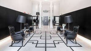 Una hall moderna con poltrone in pelle nera, un pavimento a scacchi e un lampadario.