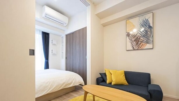 A modern hotel room with a bed, a sofa, a coffee table, and a painting on the wall. - Park Axis Honjo Azumabashi South Residence (Tokyo)