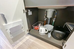 A compact kitchenette with a coffee maker, kettle, and a small trash bin. - Park Axis Honjo Azumabashi South Residence (Tokyo)