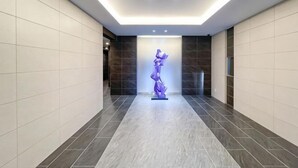 A hallway with a modern design, featuring a central sculpture and a combination of light and dark tiled floors. - Park Axis Honjo Azumabashi South Residence (Tokyo)