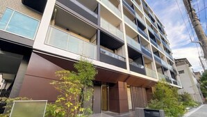 A modern multi-story building with balconies, a sign indicating a park axis, and a well-maintained entrance area with greenery. - Park Axis Honjo Azumabashi South Residence (Tokyo)