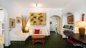 Un salón con un sofá blanco, una mesa de centro y una zona de comedor con una mesa y sillas.