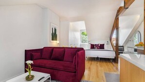 A compact living space with a red sofa, a white coffee table, and a bed with a white headboard.