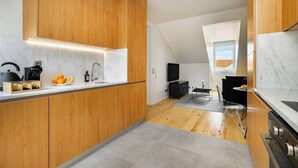 Eine moderne Küche mit Holzschränken, einer Marmorarbeitsplatte und einem eingebauten Backofen.