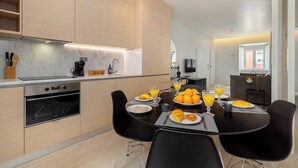 Eine moderne Küche mit Essbereich, ausgestattet mit Backofen, Kaffeemaschine und Frühstücksbereich mit Orangensaft und Croissants.