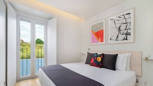 Ein Schlafzimmer mit einem großen Bett, einem Balkon mit Blick und zwei abstrakten Gemälden an der Wand.