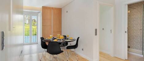 A modern dining area with a wooden cabinet, a table set with plates and glasses, and black chairs.