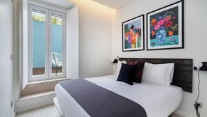 A bedroom with a large bed, a window with a view, and two framed artworks on the wall. - Lisbon Prime Aparts - BeatoHub (Lisboa)